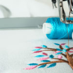 Picture of workspace in the embroidery machine close up look under the needle, lovely tree minimal sytle on background have two colorfull thread cyan and pink.