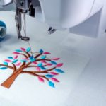Close up picture of embroidery machine 
and two threads cyan and pink color.